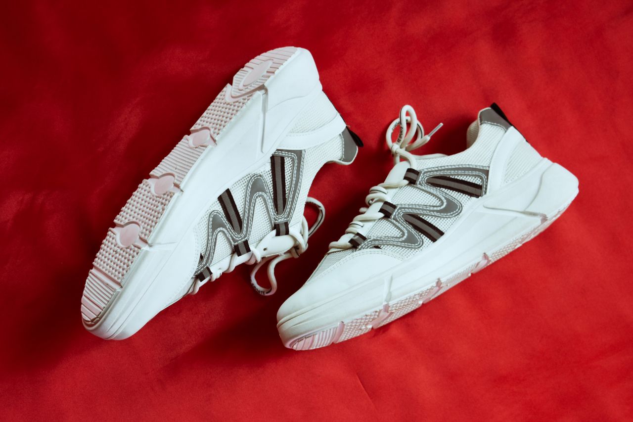 services-04 Stylish white sneakers showcased against a vibrant red backdrop, emphasizing contemporary design.
